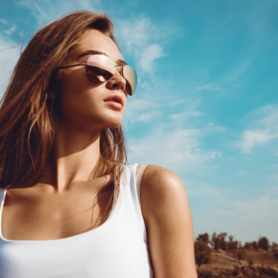 A woman wearing aviator sunglasses against the backdrop of a blue sky