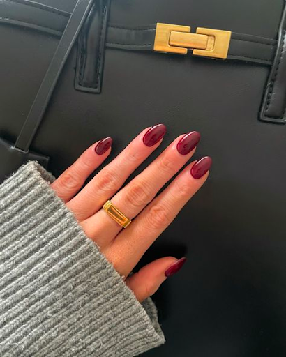 Dark pink, maroonish-colored nail polish on a woman's hand