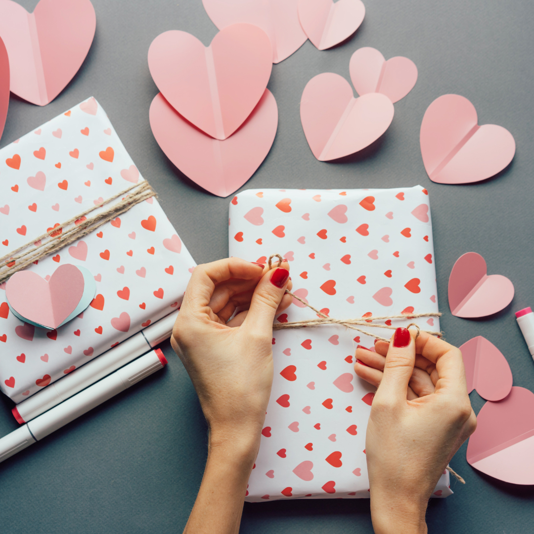 Woman wrapping a gift with heart-themed wrapping paper